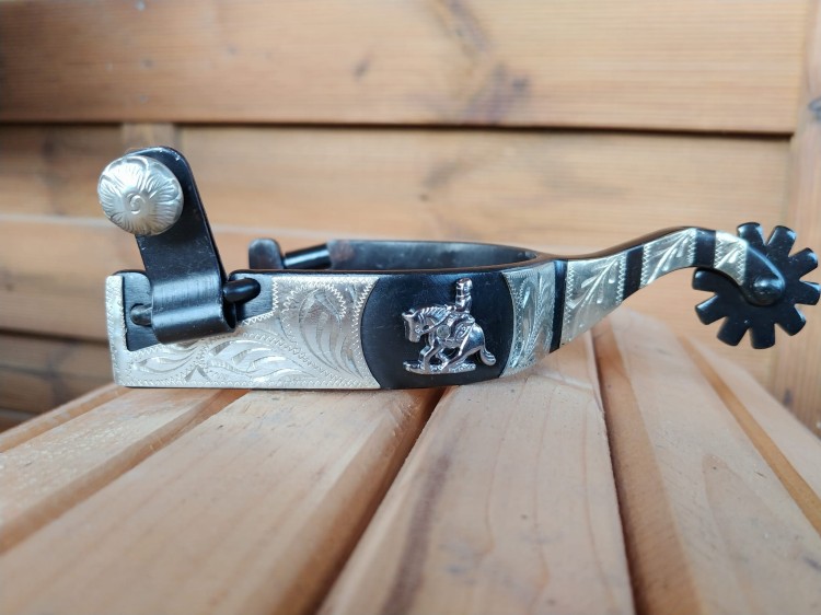 Ostrogi Equi Sliding Stop na drewnie — klamra z medalionem, widok z lewej