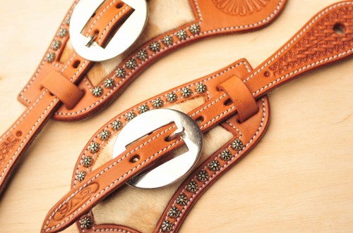 Detal: flower studs wzdłuż krawędzi i okrągła roper buckle — paski GVR z sierścią