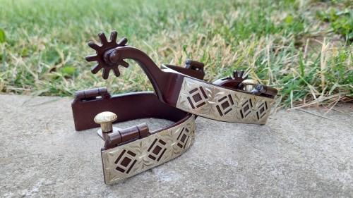 Para ostróg western AHE na betonie  widok nakładki rombowej i złotego guzika