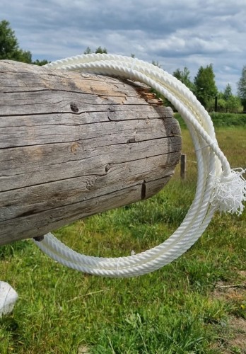 Lasso Weaver Leather 7/16" × 30' białe z hondą — zawieszone na belce, widok pełny na tle pastwiska