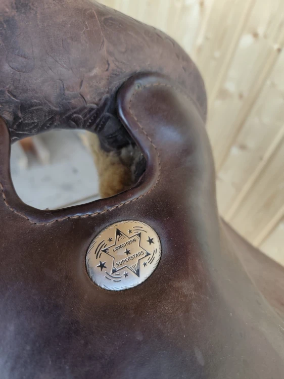 Concha Longhorn Superstars na hornie siodła western — floral tooling w tle